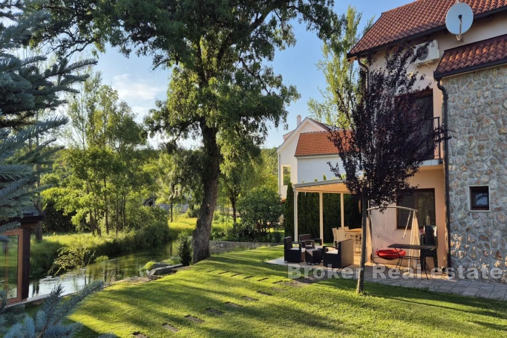 Detached house by the river with a pool and landscaped garden